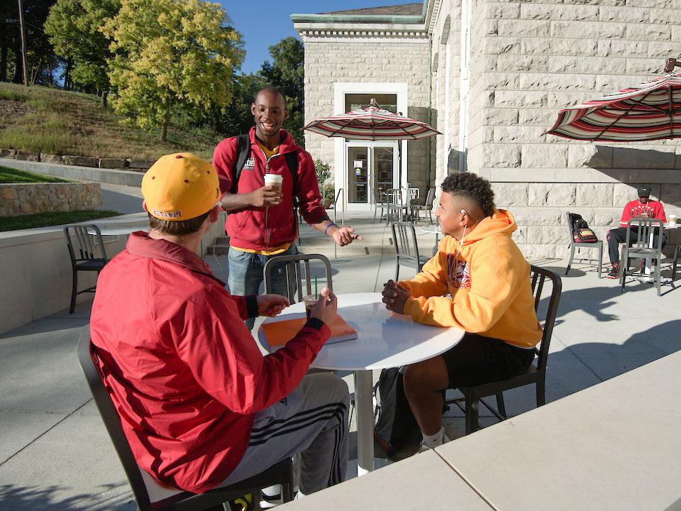students talking outside at table